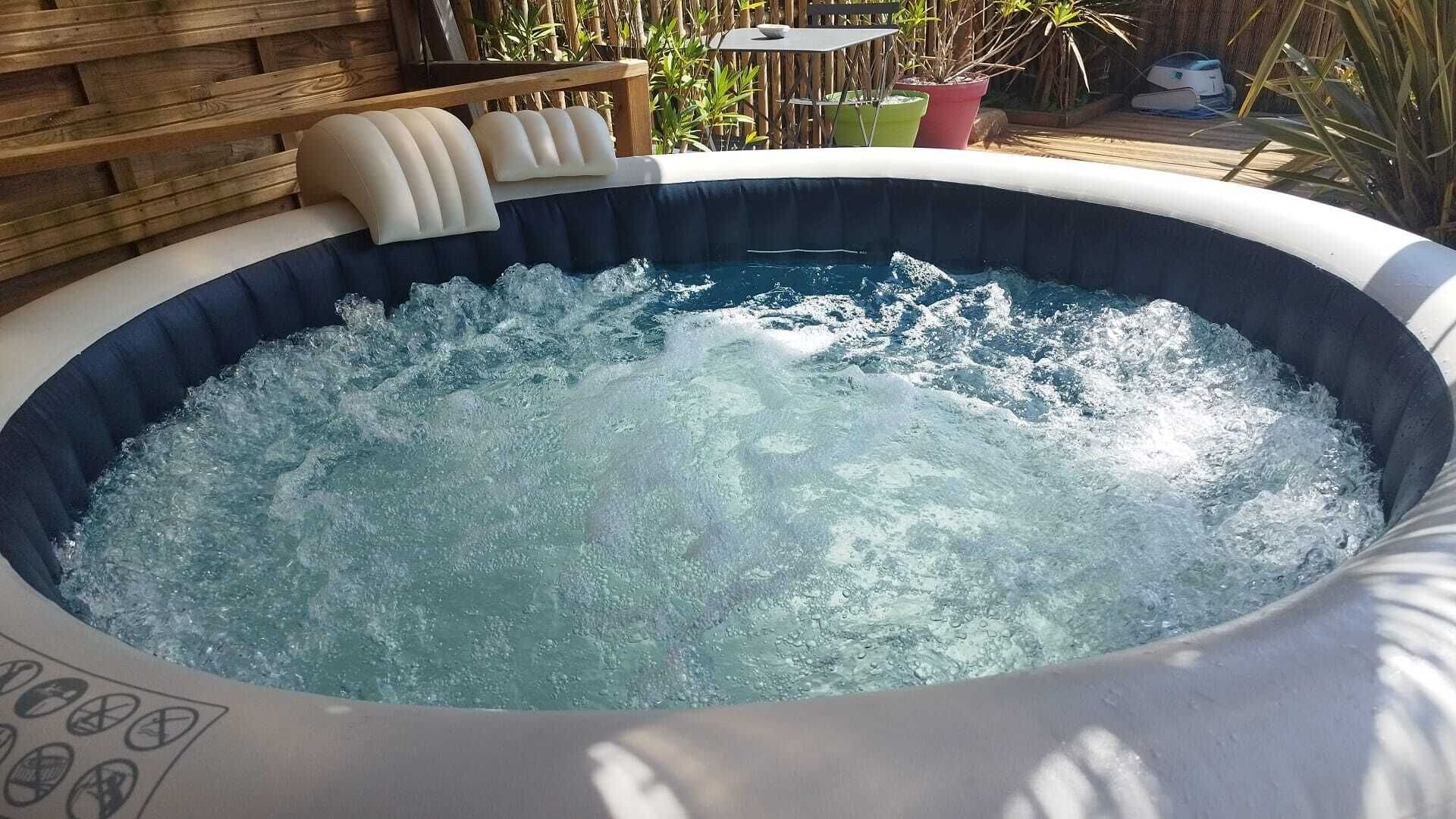 A hot tub with a wooden deck and outdoor furniture in the background.