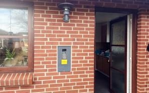 A brick building with a window, a door, and a wall-mounted light fixture. - 4 Person Holiday Home in Norre Nebel (Norre Nebel)