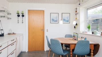Un comedor con una mesa de madera, dos sillas azules, un armario blanco y una ventana con vistas.