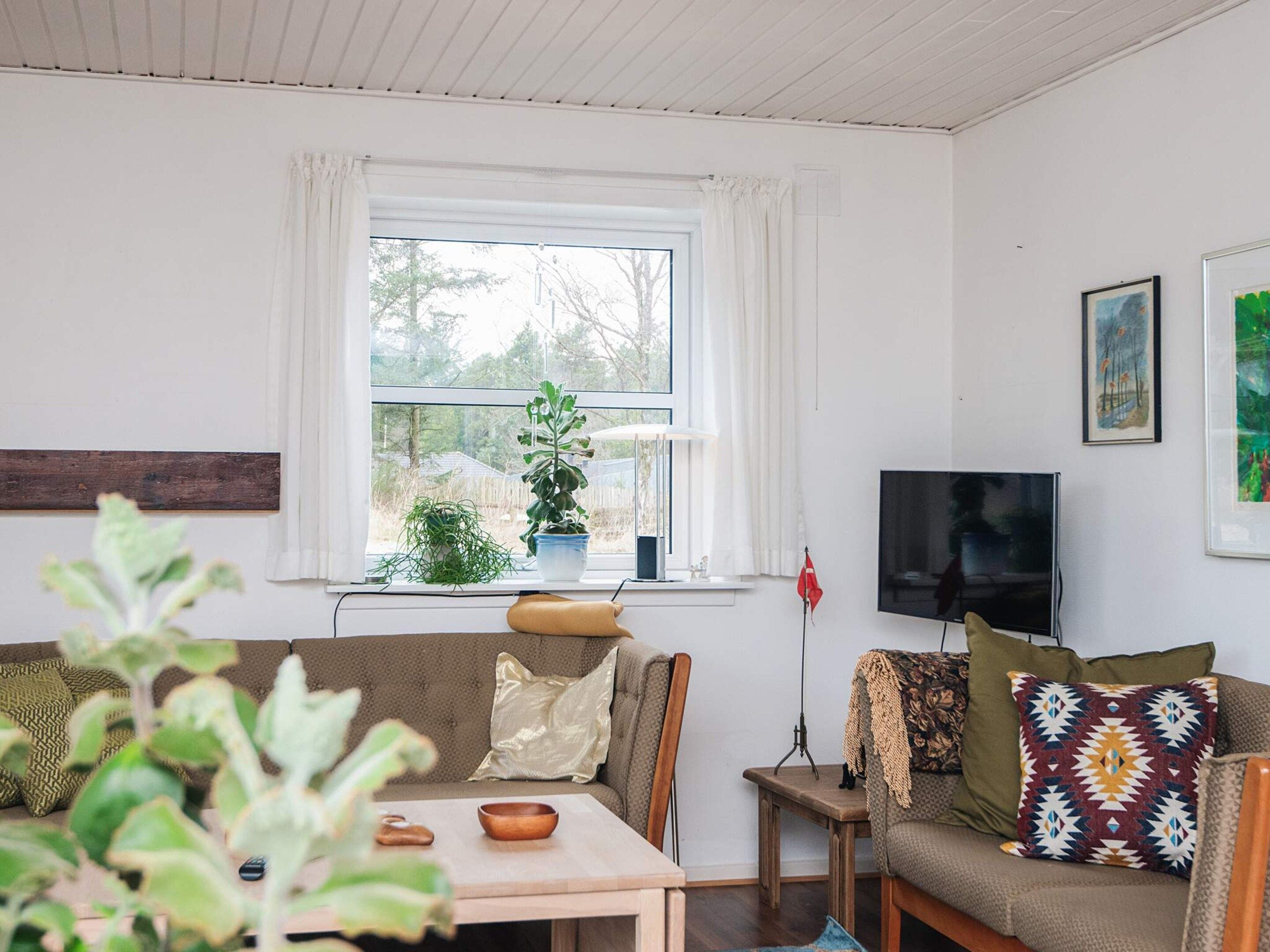 A living room with a sofa, a coffee table, a television, and a window with curtains.