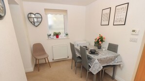 A dining area with a table set for four, a potted plant, and a heart-shaped mirror on the wall. - The Annex at Ryefield Lodge (Holmfirth)