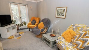 A living room with a sofa, two armchairs, a coffee table, a TV stand, and a window with blinds. - The Annex at Ryefield Lodge (Holmfirth)