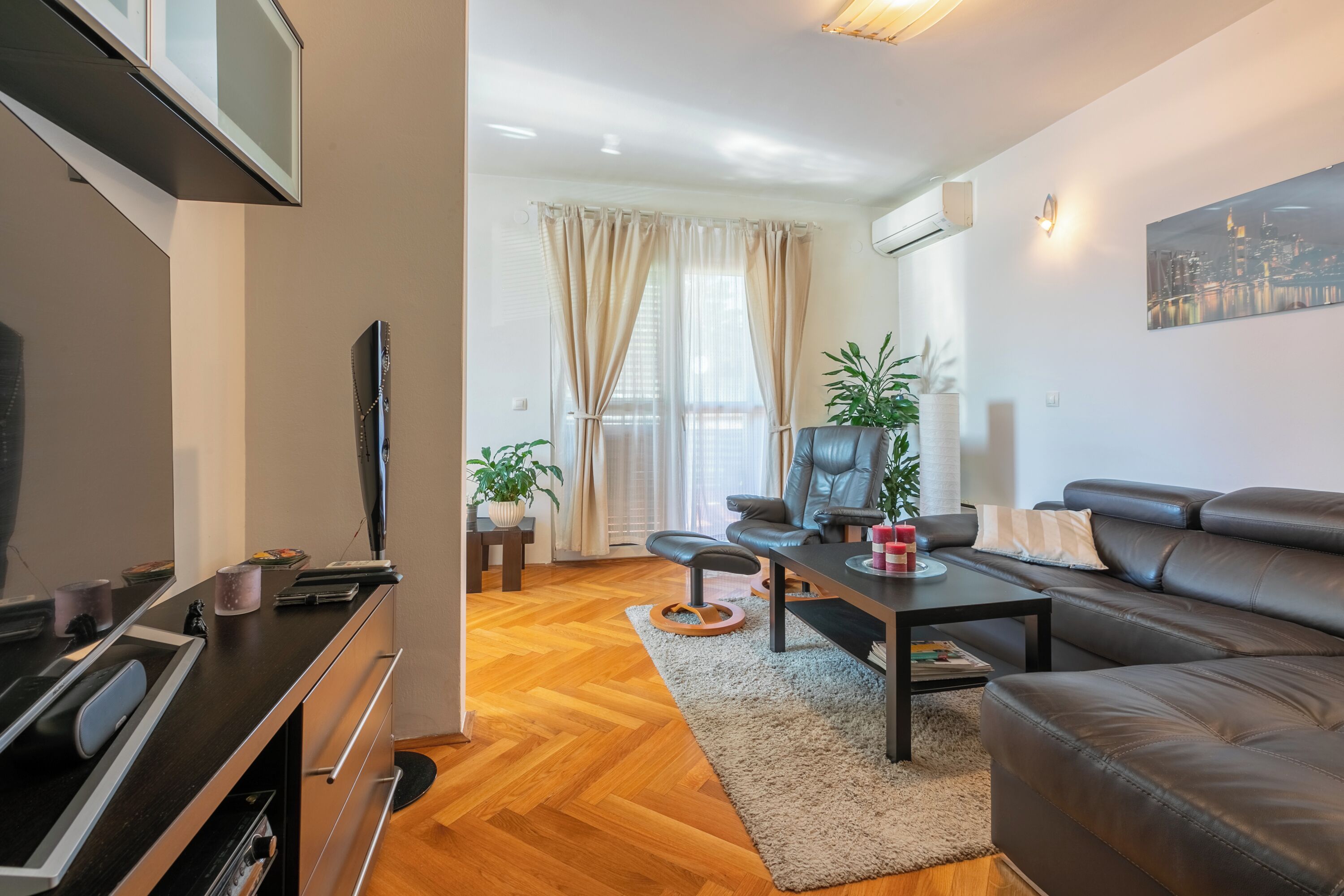 A modern living room with a sofa, a coffee table, a TV, and a fireplace.