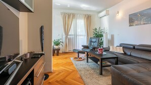 Een moderne woonkamer met een bank, salontafel, televisie en open haard.