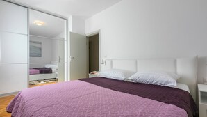 Een slaapkamer met een bed, een kledingkast en een nachtkastje.