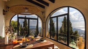Zona pranzo con tavolo apparecchiato per la colazione, ampie finestre ad arco e vista sul paesaggio.