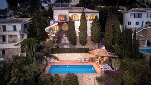 Una villa con piscina, area salotto esterna e una scalinata in pietra che conduce all'ingresso.