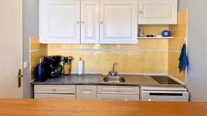A kitchen with white cabinets, a stainless steel sink, and a countertop with a coffee maker and utensils. - Sea view, Terrace Secured parking near beach railway station and park (Villeneuve-Loubet)