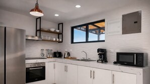 A modern kitchen with stainless steel appliances, white cabinetry, and a window with a view. - Villa 3 bedrooms / 3 bathrooms • Private swimming pool - Tamarindo (Tamarindo)