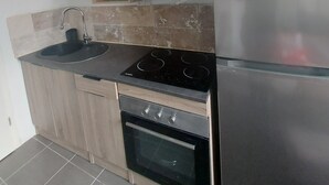 A modern kitchen with a stainless steel refrigerator, a built-in oven, a sink, and wooden cabinetry.
