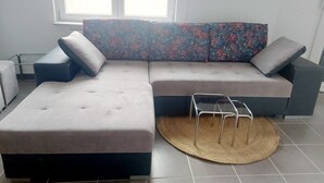 A modern living room with a sectional sofa, a small ottoman, and a woven rug.