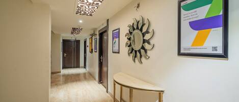 A hallway with a marble floor, a wall-mounted mirror, and framed artwork.