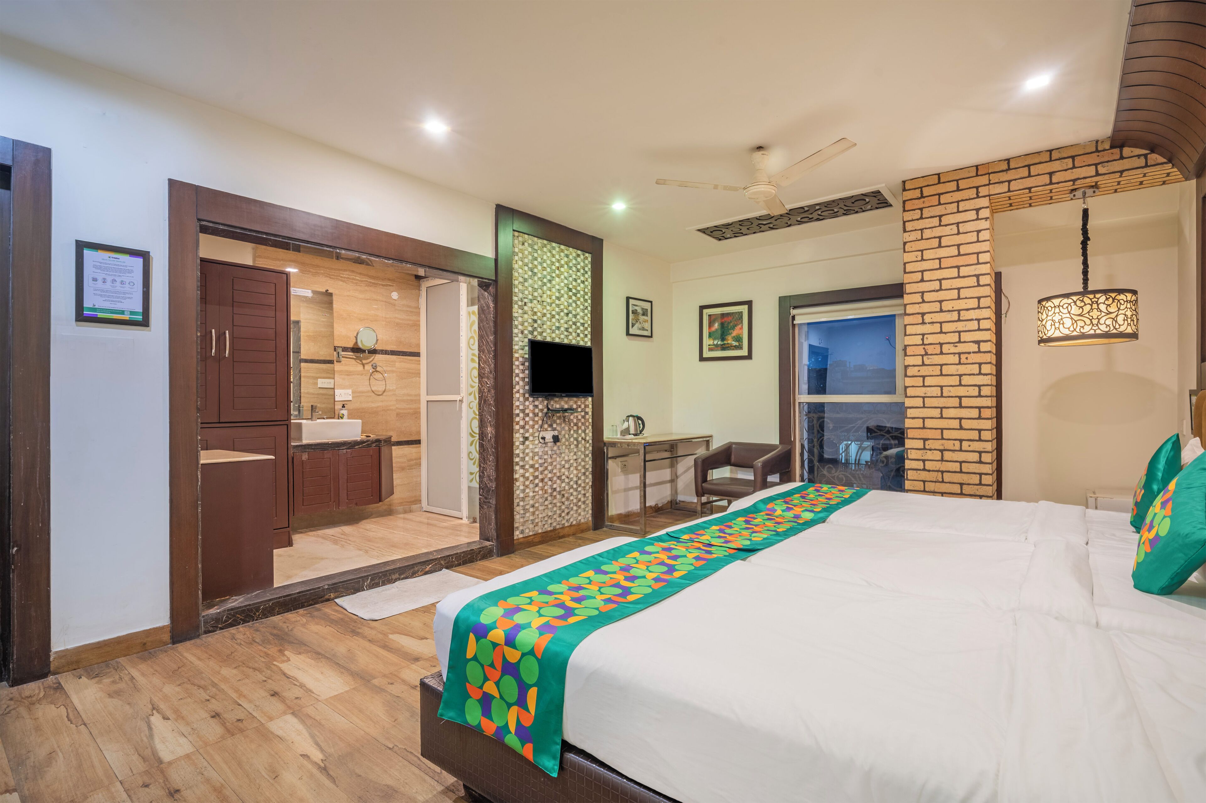 A hotel room with a bed, a desk, a chair, a TV, and a bathroom.