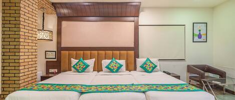 A hotel room with a large bed, a brick wall, a wooden headboard, and a glass table.