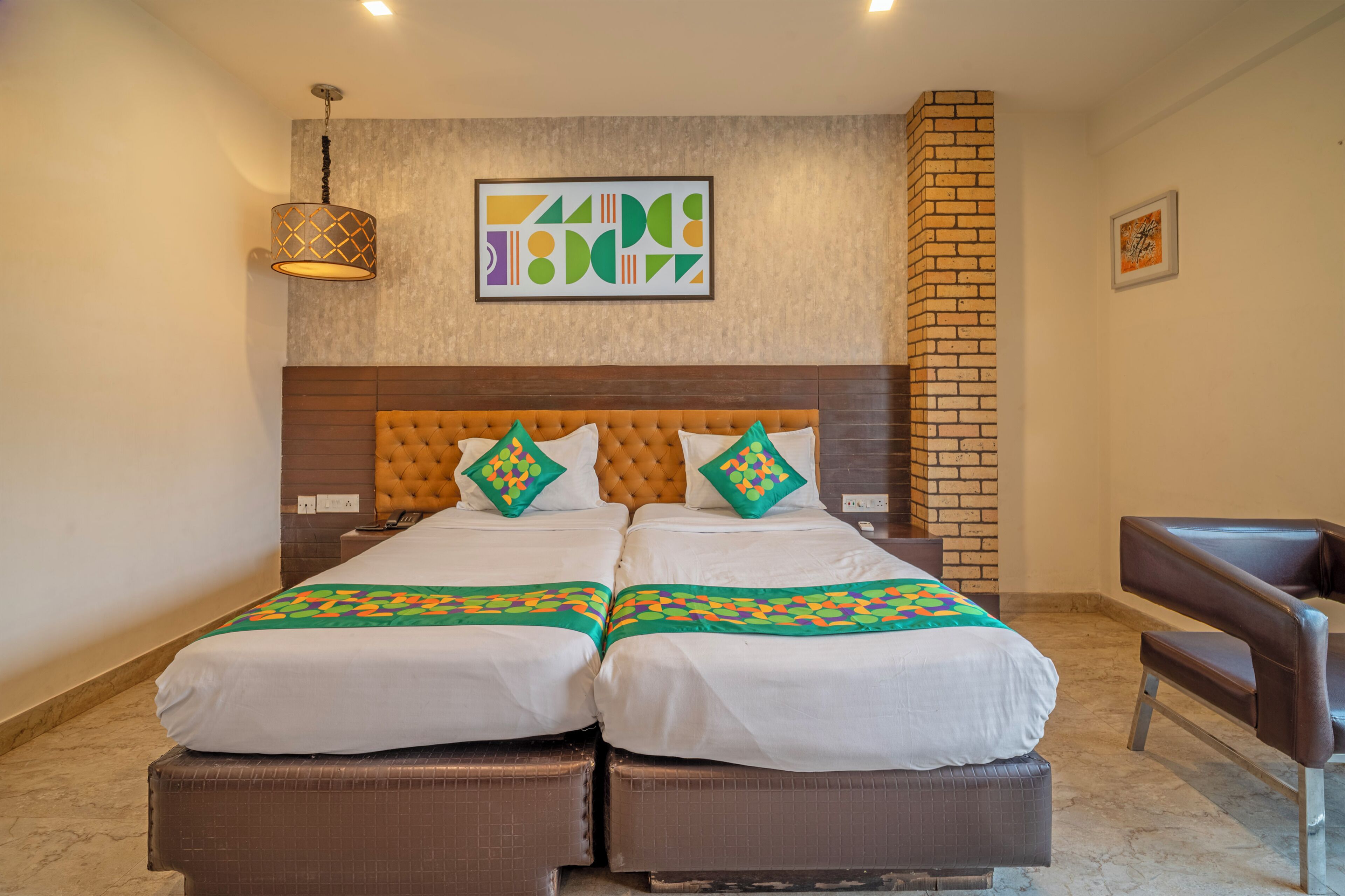 A double bed with a wooden headboard, two bedside tables, a hanging lamp, and a brick accent wall.