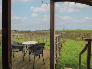 Eine Holzterrasse mit Korbmöbeln und Blick auf einen Weinberg.