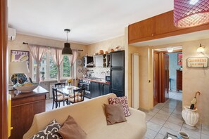 Un salon confortable avec un canapé, une table à manger et un coin cuisine équipé de placards et d’appareils électroménagers.