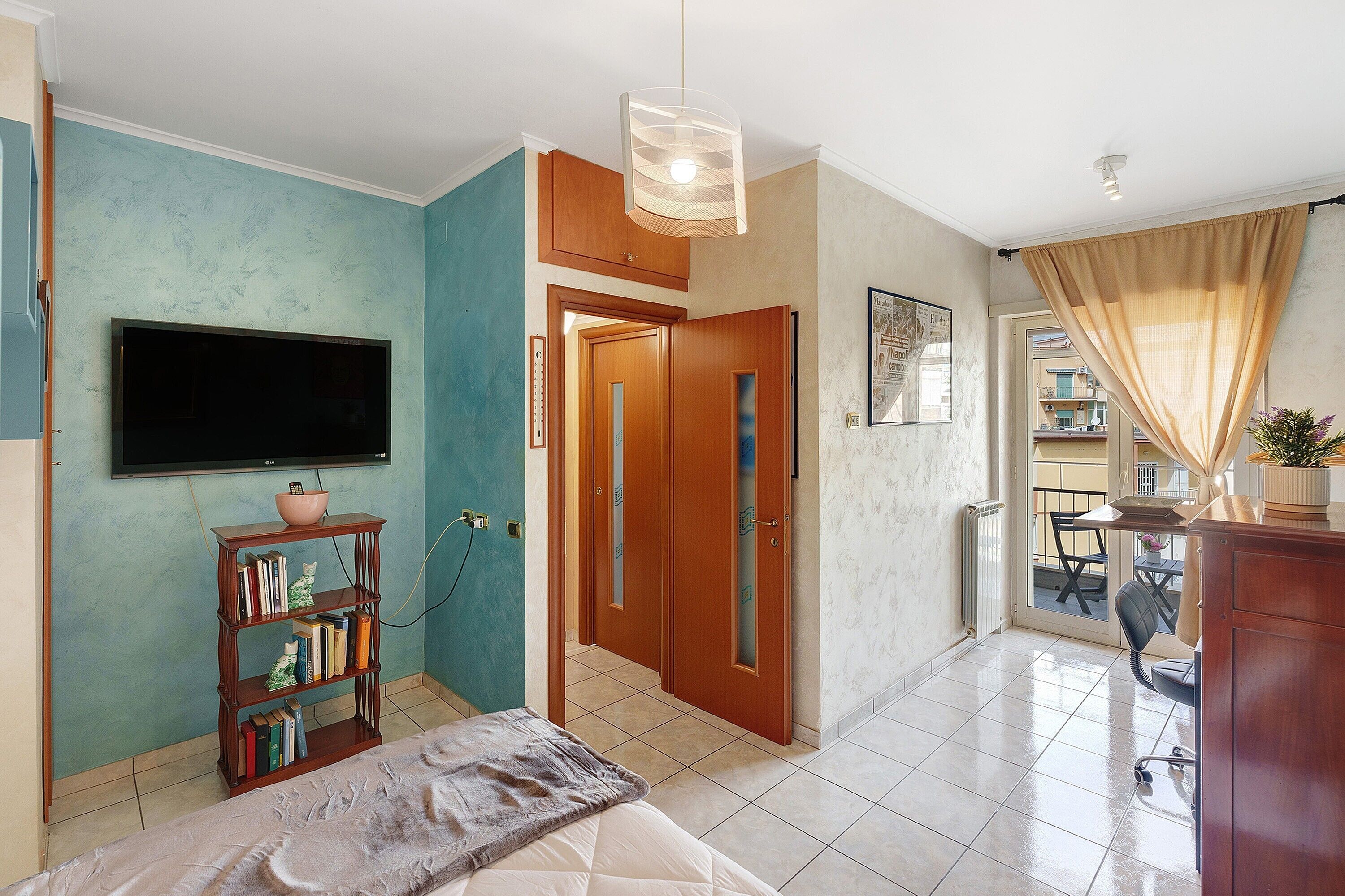 A living room with a TV, bookshelf, and a dining area with a table and chairs.