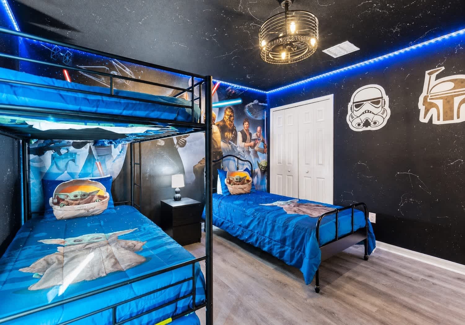 A room with bunk beds, Star Wars-themed wall art, and a Star Wars character cutout.