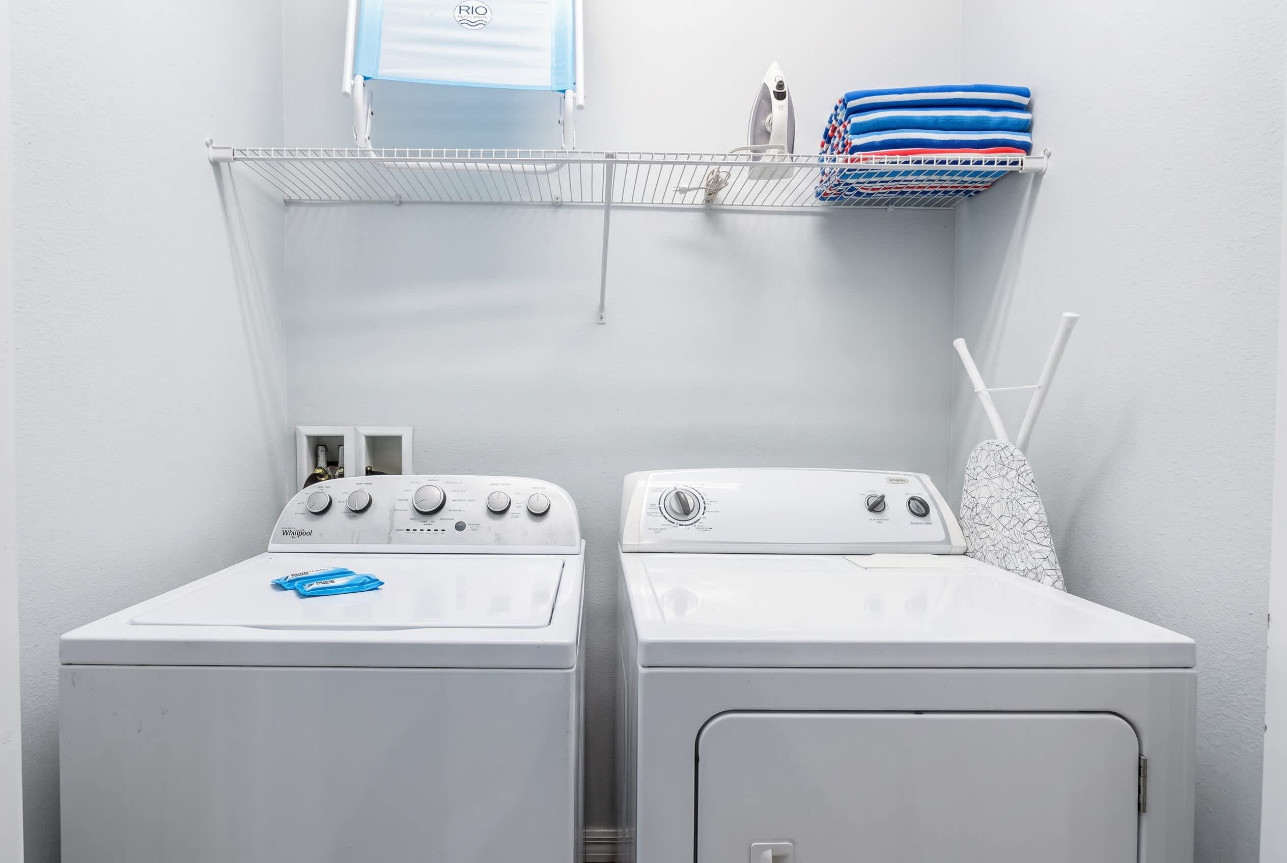 A laundry area with two front-loading washers and a drying rack above.