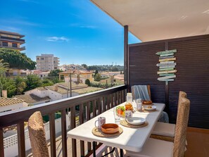 A balcony with a table set for breakfast, a view of the city, and a signboard with various names. - Iona (L'Escala)