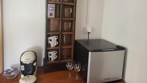 Een kitchenette met een Bosch koffiezetapparaat, een Klasen koelkast en een kastje met bekers en glazen.