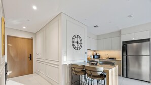A modern kitchen with a central island, stainless steel appliances, and a wooden door. - Luxury Burj Royale 2BR Burj Khalifa & Fountain View With Balcony by Evoke (Dubai)