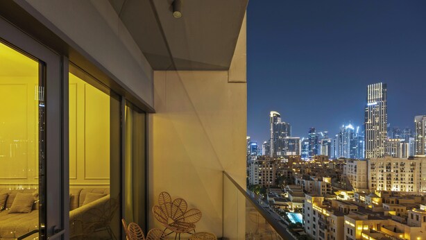 A balcony with a cityscape view, a sofa, and a chair. - Luxury Burj Royale 2BR Burj Khalifa & Fountain View With Balcony by Evoke (Dubai)