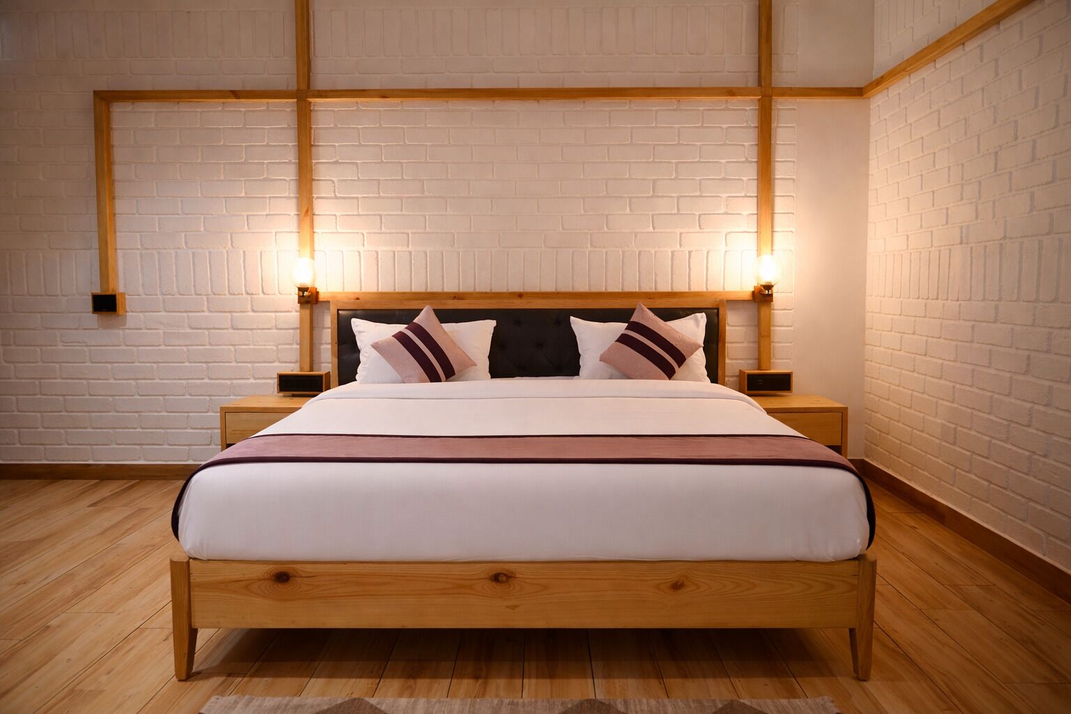 A bed with a wooden frame, white bedding, and two bedside tables with lamps.