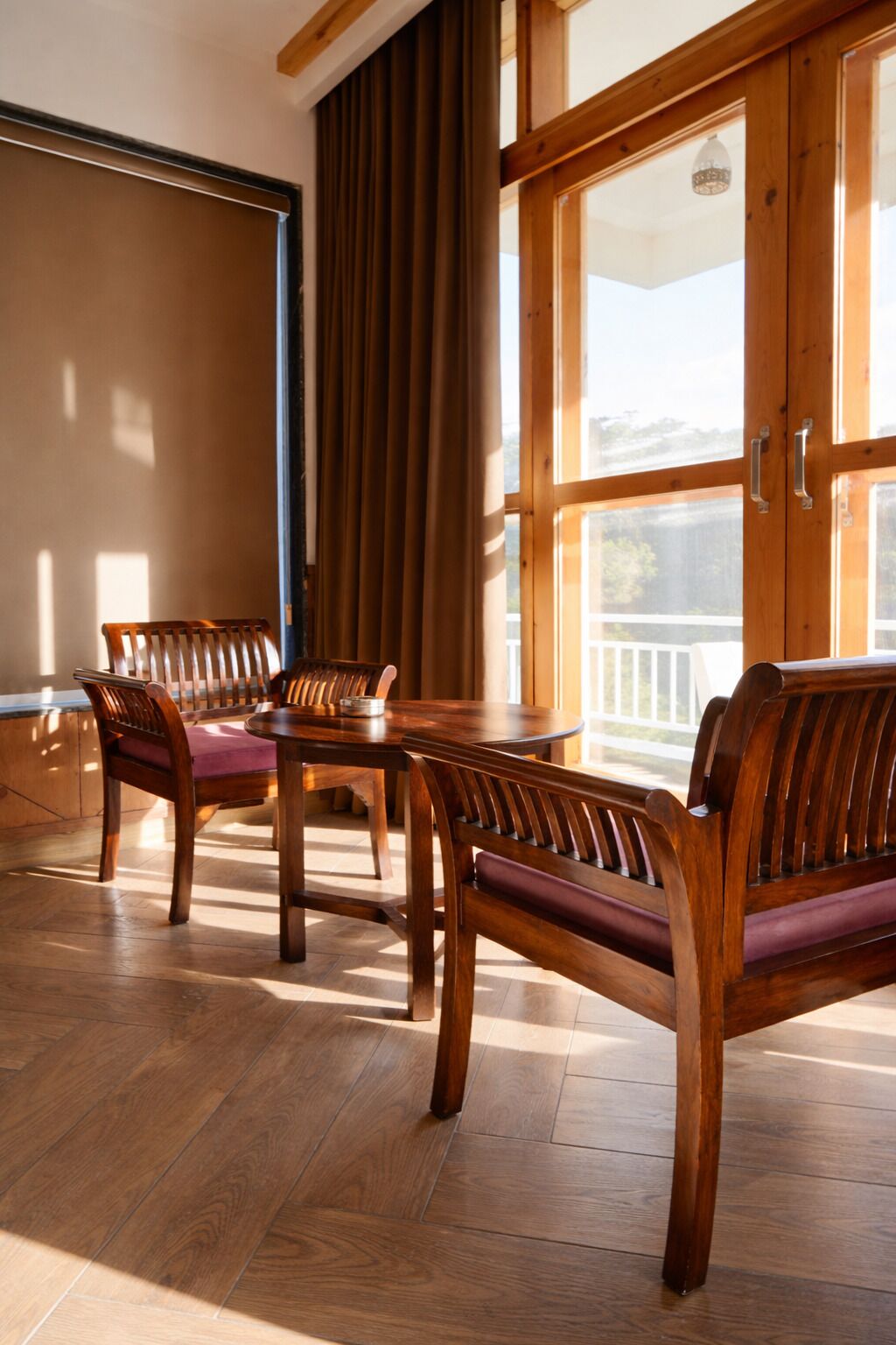 A room with a wooden dining table and benches, large windows, and a view of the outdoors.