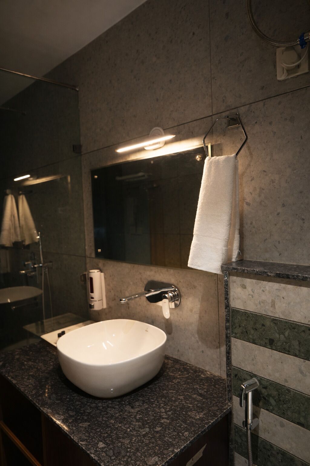 A bathroom with a white sink, a towel hanging on a rack, a mirror, and a shower area.