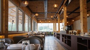 Un restaurant au décor intérieur en bois, avec de longues tables et des lampes suspendues.