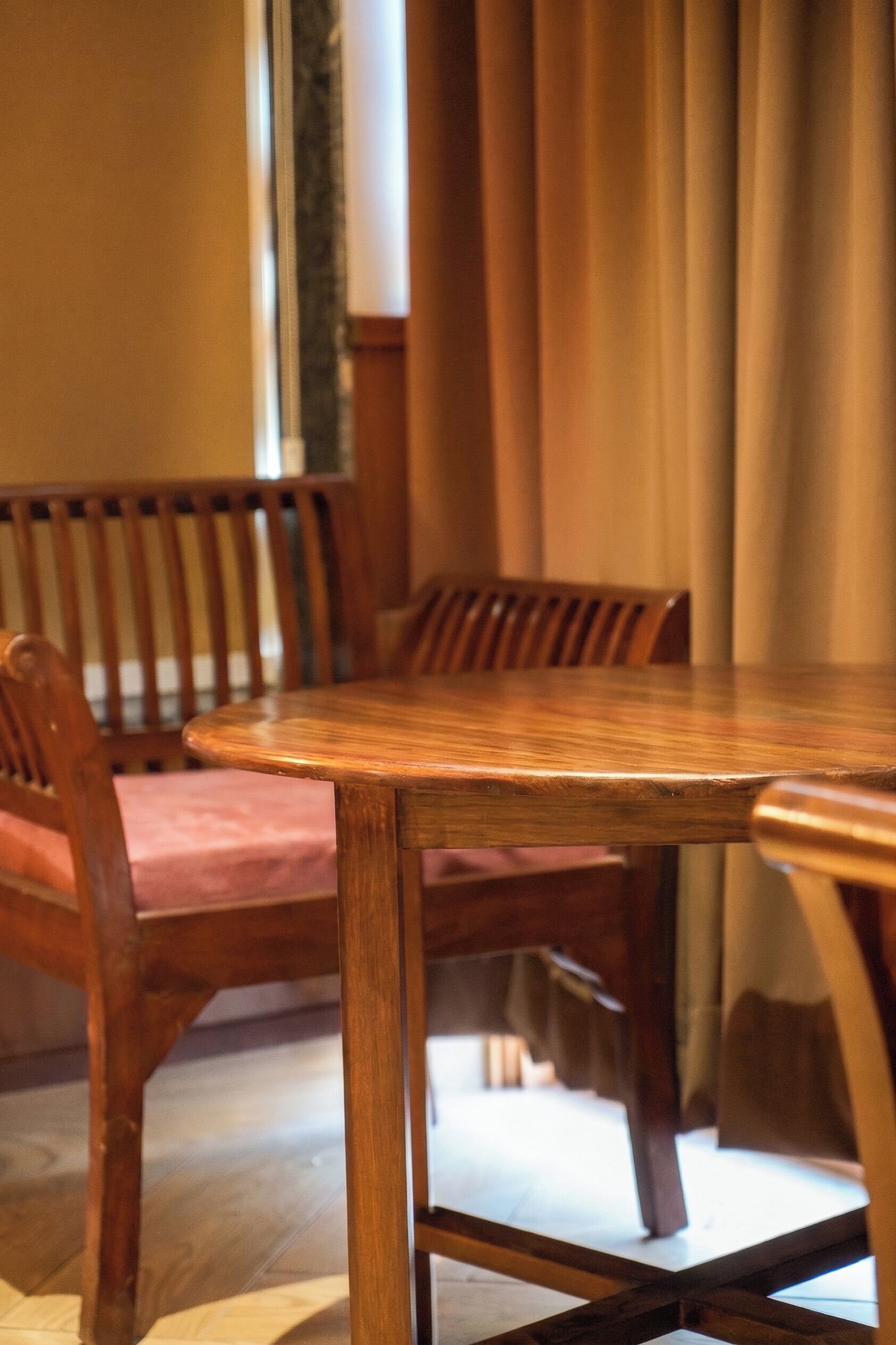 A wooden dining table with chairs, a window, and curtains.