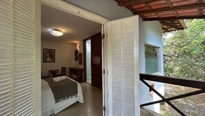 Ein Schlafzimmer mit einem Bett, einem Nachttisch, einer Fensterbank und Blick auf Grünfläche.