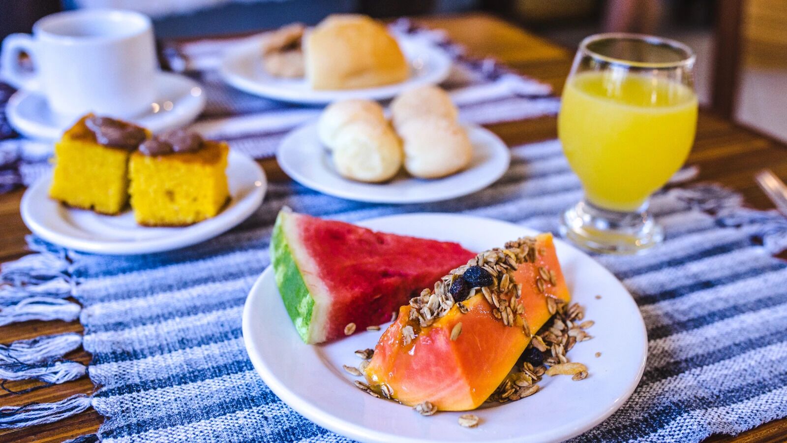 A breakfast setting with plates of food, a cup, and a glass of juice on a table.