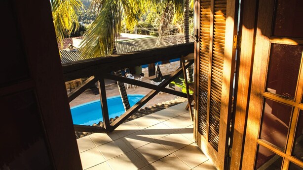 Vista di una piscina da un balcone in legno, con pavimento piastrellato e ringhiera in legno.