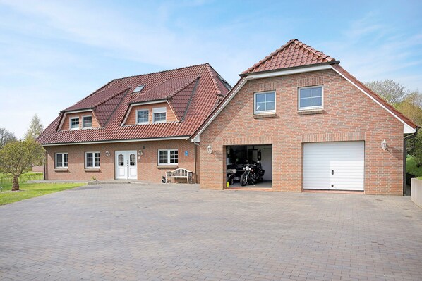 Ein zweistöckiges Haus mit Garage, gepflasterter Auffahrt und einem kleinen Garten.