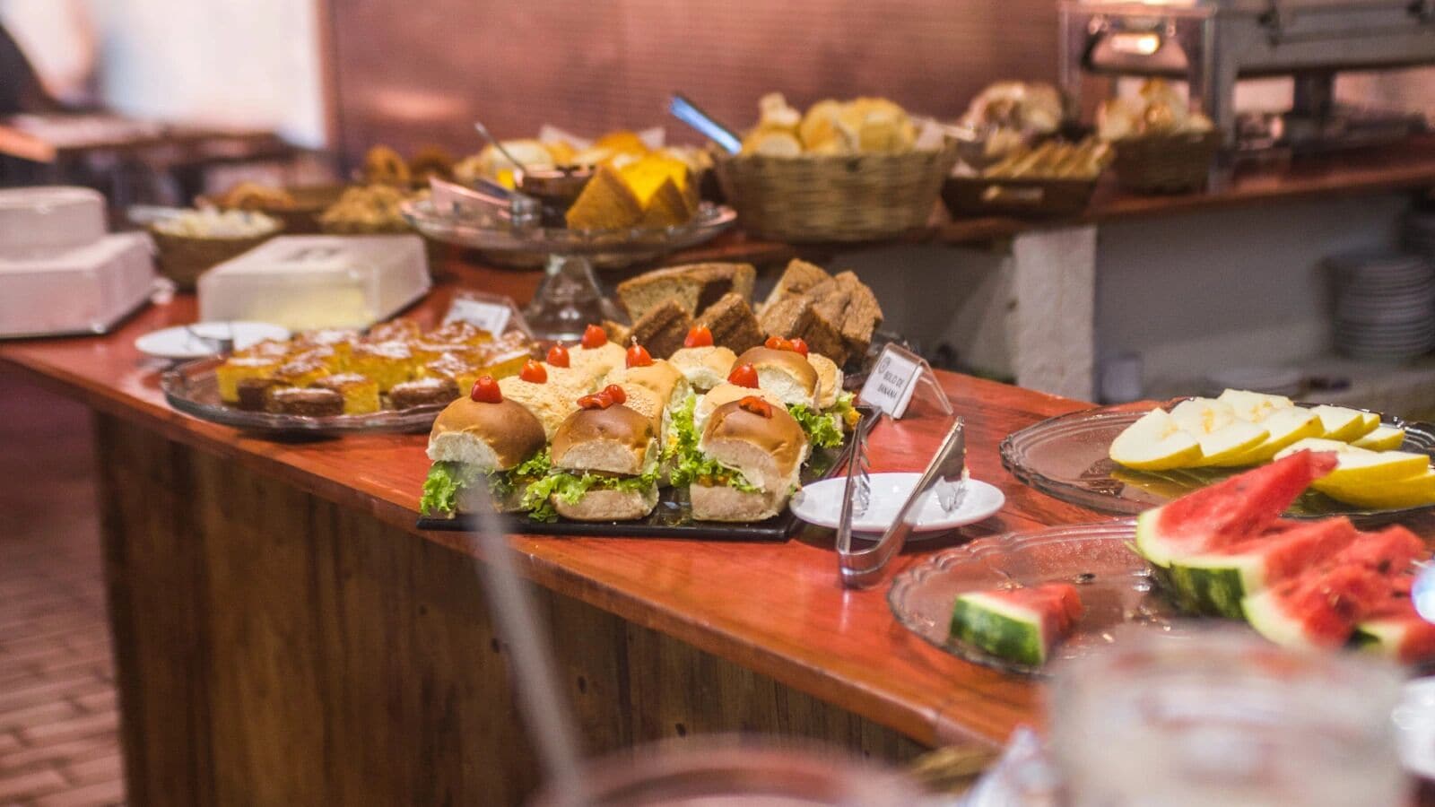 A buffet with various food items including sandwiches, fruits, and desserts.