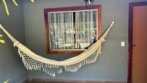 A hammock hanging between two windows with a view of a building outside. - Pousada Meraki (Santana do Riacho)