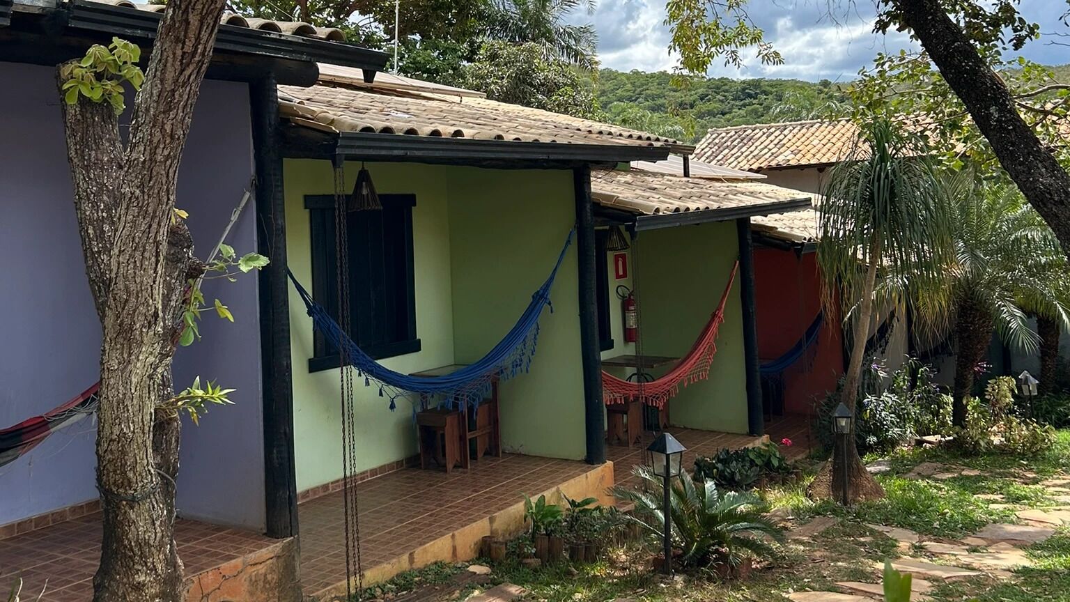 Una casa con techo de tejas, una hamaca y un pequeño jardín.