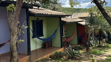 Una casa con techo de tejas, una hamaca y un pequeño jardín.