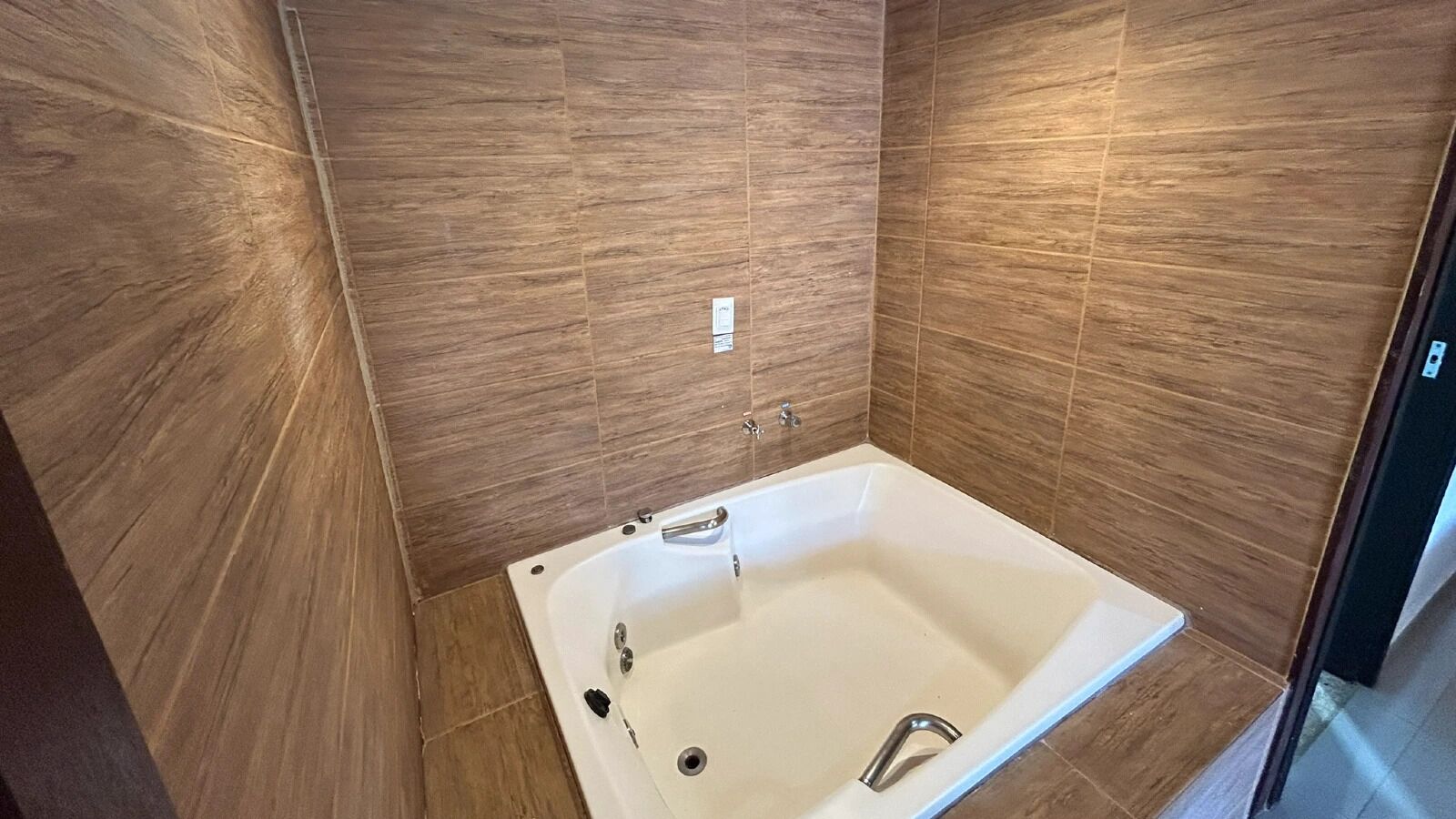 A modern bathroom with a freestanding bathtub, tiled walls, and a visible electrical outlet.