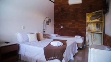 Habitación de hotel con dos camas, una mesita, una lámpara de pared y una pared de ladrillo.
