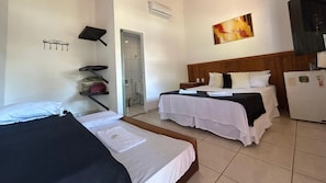 A hotel room with two beds, a shower area, a refrigerator, and a painting on the wall.