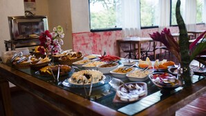 A buffet with various dishes, a microwave, and a window with a view of greenery.