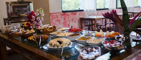 A buffet with various dishes, a microwave, and a window with a view of greenery.