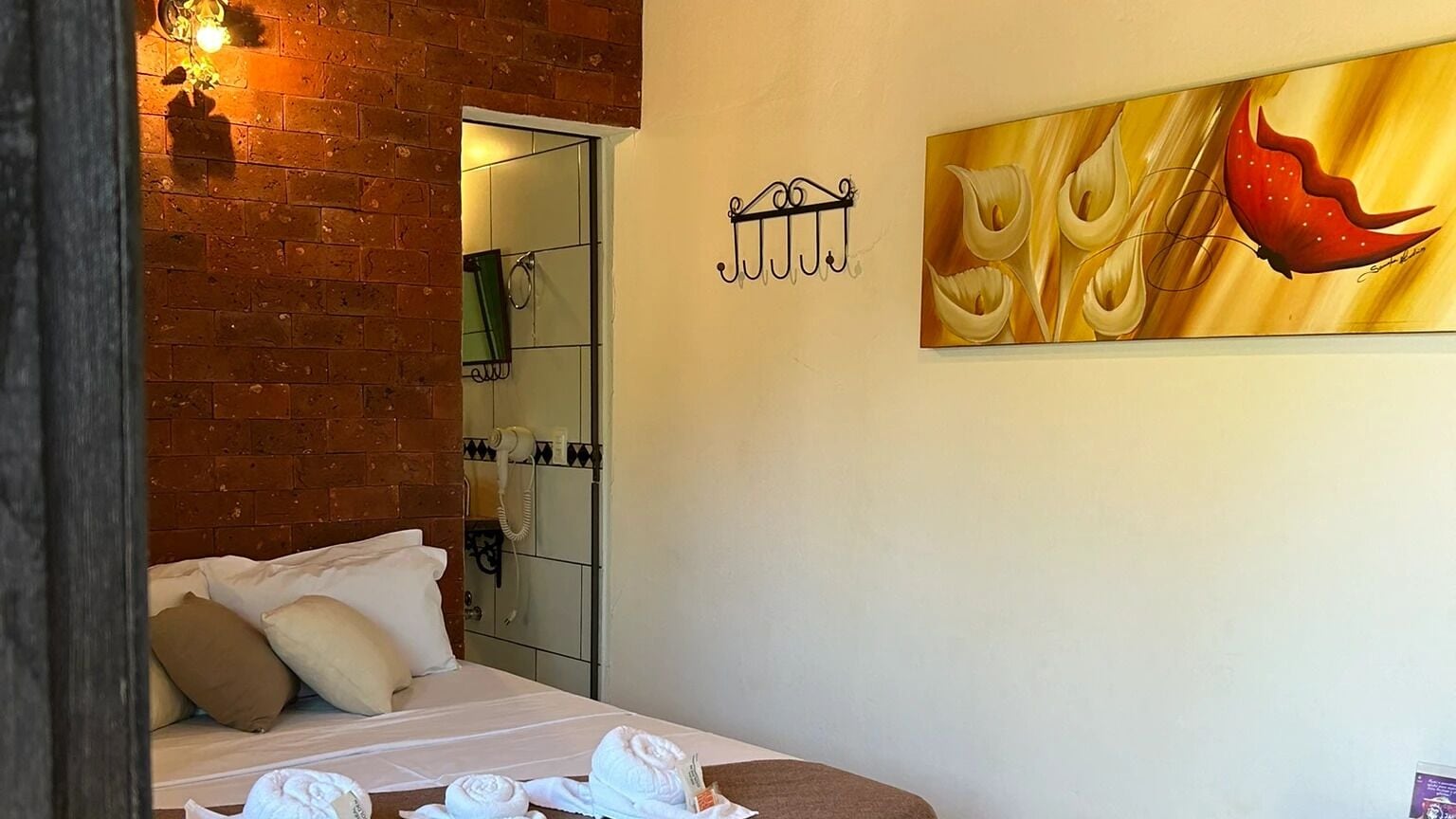 Habitación de hotel con una cama, un cuadro, un teléfono y una pared de ladrillo.