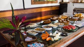 A buffet with various food items and a plant on the left.