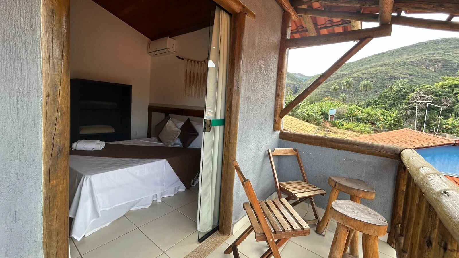 A balcony with a wooden railing, a bed with a white sheet, and a chair.