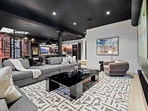 A modern living room with a sofa, coffee table, and a television. - RoofTopPatio–HotTub–FirePit-WetBar-Downtown (Cleveland)